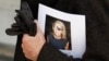 FILE - A man holds a sign honoring Sunday Times journalist Marie Colvin after a memorial service, outside St Martin in the Field in London, May 16, 2012. 