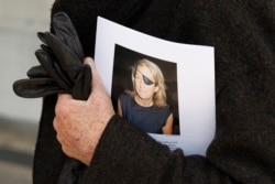 FILE - A man holds a sign honoring Sunday Times journalist Marie Colvin after a memorial service, outside St Martin in the Field in London, May 16, 2012.