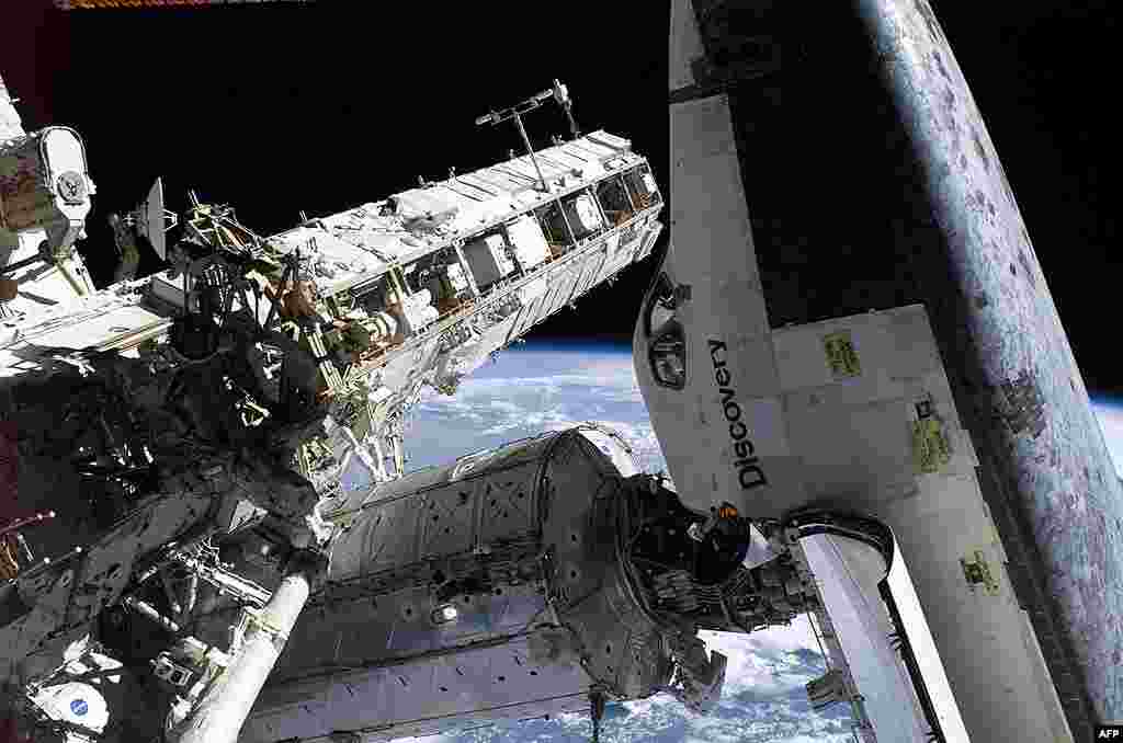 Dwarfed by the station and shuttle, astronaut Soichi Noguchi conducts a spacewalk, August 3, 2005. (NASA) 
