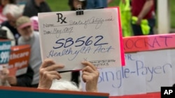 Caroline Elam holds up a mock prescription order calling for passage of SB562, a single-payer health care bill, during a march to the Capitol in Sacramento, Calif., April 26, 2017.