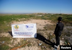 FILE - An Iraqi police officer looks at a Yazidi mass grave site near Sinjar, Iraq, Feb. 4, 2019.