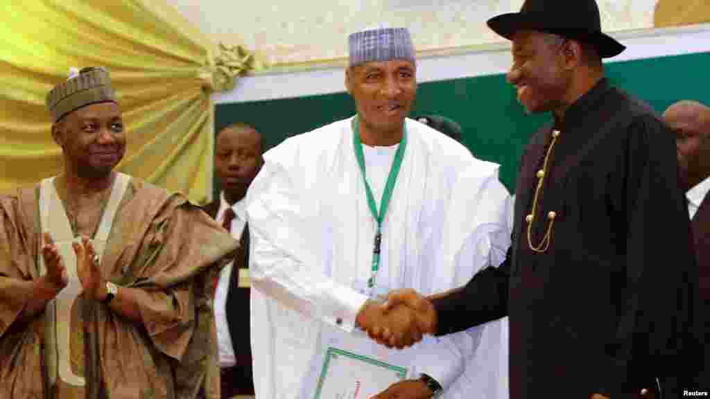 Nigeria's President Goodluck Jonathan (R) shakes hands with Muhammad Tukur Modibbo, managing director of Aura Energy Ltd, as Vice President Namadi Sambo (L) applauds.