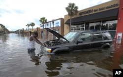 A man tries to figure out how to salvage his flooded vehicle in the wake Hurricane Irma, Sept. 11, 2017, in Jacksonville, Florida.