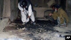 Afghan men investigate the site of a shooting incident in Kandahar province, March 11, 2012