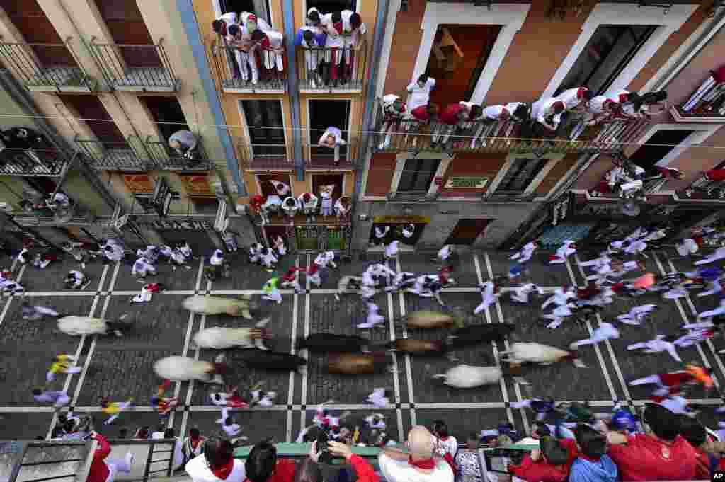 People run next to fighting bulls during the running of the bulls at the San Fermin Festival, in Pamplona, northern Spain.