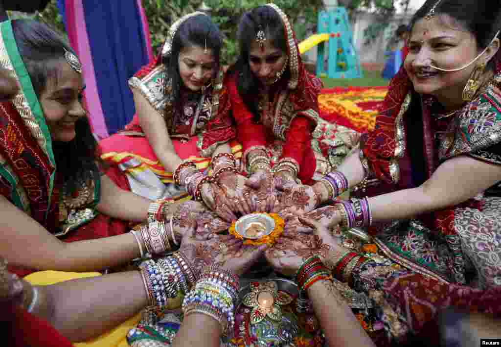 Women with their hands decorated with henna paste pose for pictures as they pray during the Hindu festival of Karva Chauth in Ahmedabad, India. Married Hindu women observe a one-day fast and offer prayers for the well-being of their husbands during the festival.