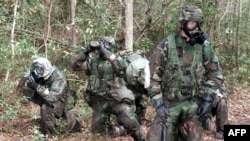 FILE - U.S. Marines take a break during an obstacle course exercise wearing protective chemical, biological gear at Camp Geiger, North Carolina, Nov. 1, 2001.