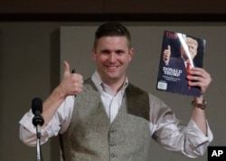 FILE - Richard Spencer, who leads a movement that mixes racism, white nationalism and populism, holds up a magazine cover showing then-President-elect Donald Trump before signing it for a supporter, Dec. 6, 2016, in College Station, Texas.