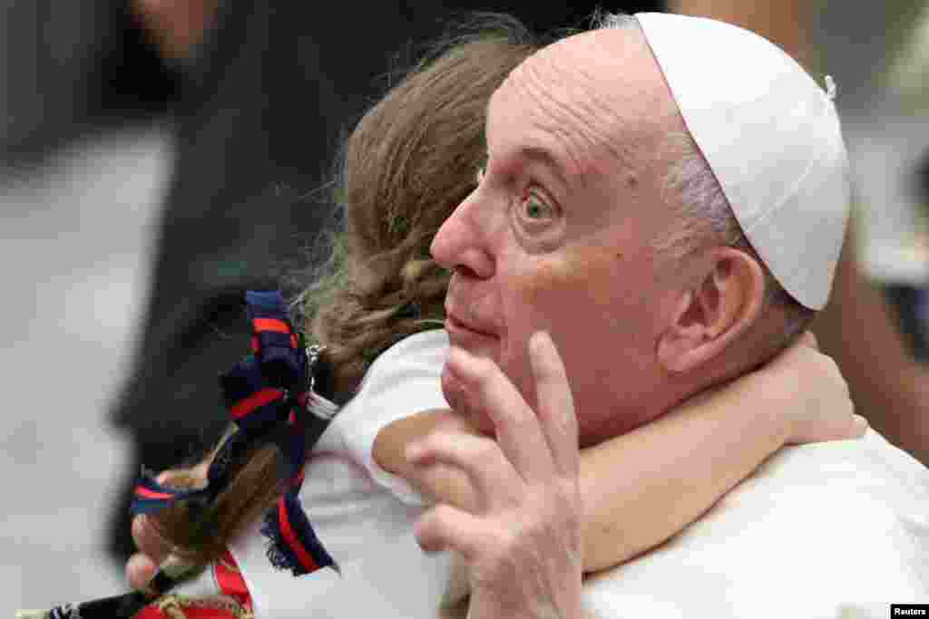 A child hugs Pope Francis during the weekly general audience in the Paul VI Audience Hall at the Vatican.