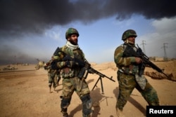 Shi'ite Popular Mobilization Forces carry their weapons, while advancing towards the city of Al-Qaim, Iraq, Nov. 3, 2017.