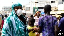 Une pèlerine de la confrérie mouride, un ordre soufi, portant un masque, arrive à la Grande Mosquée de Touba, avant la fête religieuse du Magal commémorant l'exil de son fondateur, le grand marabout Sheikh Amadou Baba, le marabout, Touba, Sénégal, 27 octo