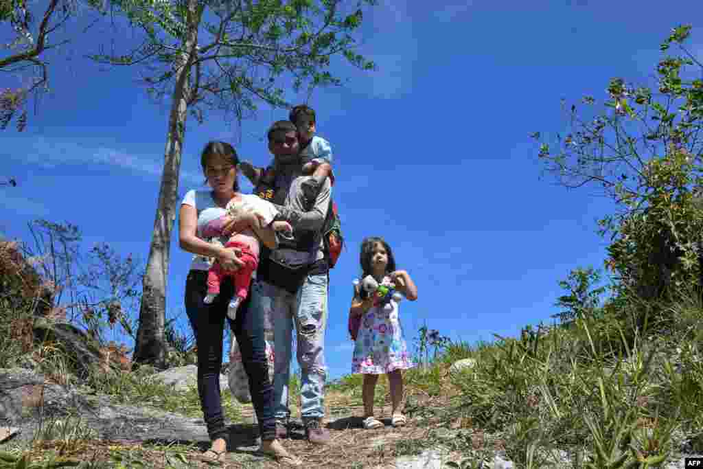 Venezuelan police officer Cesar Marcano (C) along with his wife Adriana Ballera (L) and their children are seen at the Brazil-Venezuela border, in Pacaraima, Roraima state, Brazil. More than 100 Venezuelan soldiers have deserted and crossed into Colombia, immigration authorities reported as tensions rise between the neighbors over humanitarian aid.