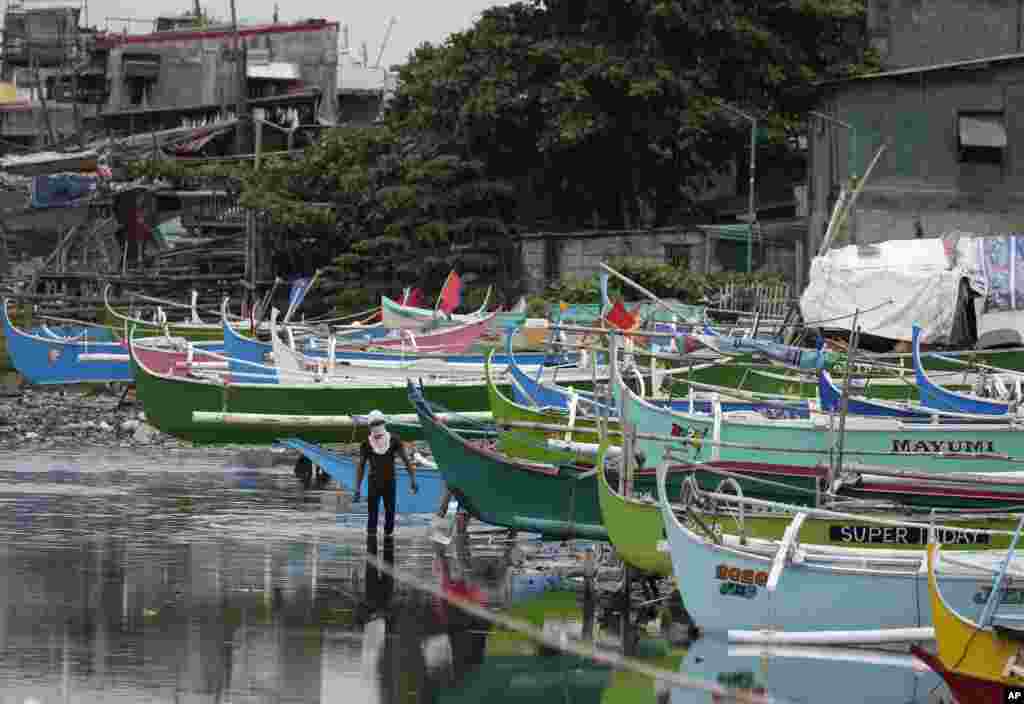 A man walks by docked fishing boats during the start of a lockdown due to a rise in COVID cases in the city of Navotas, Manila, Philippines.