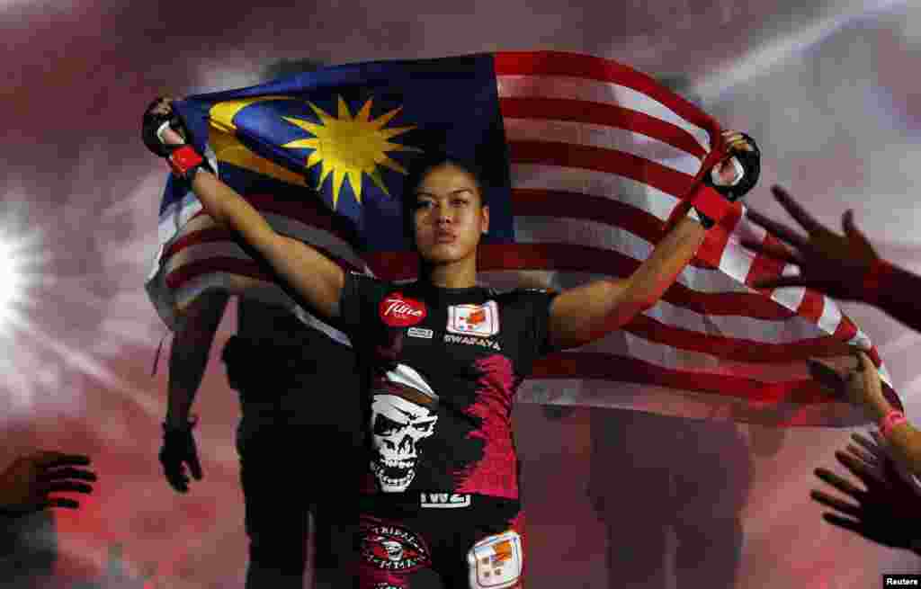 Malaysia&#39;s Ann Osman enters the arena carrying the Malaysian flag for her mixed martial arts (MMA) ONE Championship fight against Egypt&#39;s Walaa Abbas in Kuala Lumpur. Osman is the first female Muslim MMA fighter to compete at the top level of the sport.
