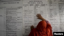 A woman leans against a ferry passenger list as she searches for information about family members who were on board a sunken ferry, at a rescue command post in Siwa, Wajo, South Sulawesi, Indonesia, Dec. 21, 2015.