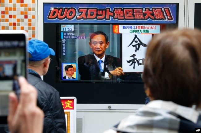 People watch a TV screen showing the name of new era 