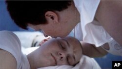 In this undated photo made available by Scott Anger & Bob Sacha for the Open Society Foundations, in Cherkasy, Ukraine, Nadezhda Zhukovsky, 50, kisses her sleeping son Vlad, who died of brain cancer last year at age 27, before going to the local pharmacy 