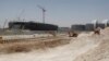 FILE - Construction cranes and bulldozers operate in Doha, June 25, 2013.