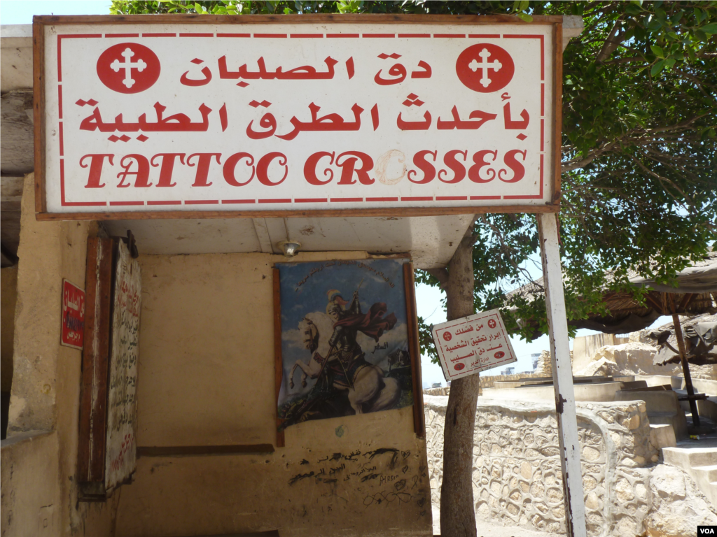 Papan tanda pembuat tato di luar Gereja Kristen Koptik St. Simon the Tanner di pinggir daerah kumuh Kairo yang disebut Kota Sampah (18/7). (VOA/S. Behn)