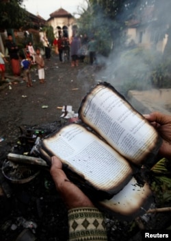 Seorang pengikut Ahmadiyah memperlihatkan Alquran yang terbakar di Ciampea, Jawa Barat, 2 Oktober 2010.