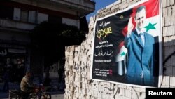 FILE - A man on a motorcycle rides past a poster depicting Syria's President Bashar al-Assad on a wall in the pro-government al-Zahraa neighbourhood in Homs, May 15, 2014.