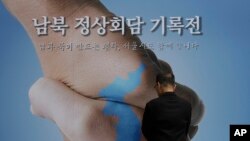 A man looks at a banner showing a map of the Korean Peninsula to wish for a successful inter-Korean summit in Seoul, South Korea, April 26, 2018. North Korean leader Kim Jong Un and South Korean President Moon-Jae-in will plant a commemorative tree and inspect an honor guard together after Kim walks across the border Friday for their historic summit, Seoul officials said Thursday. 
