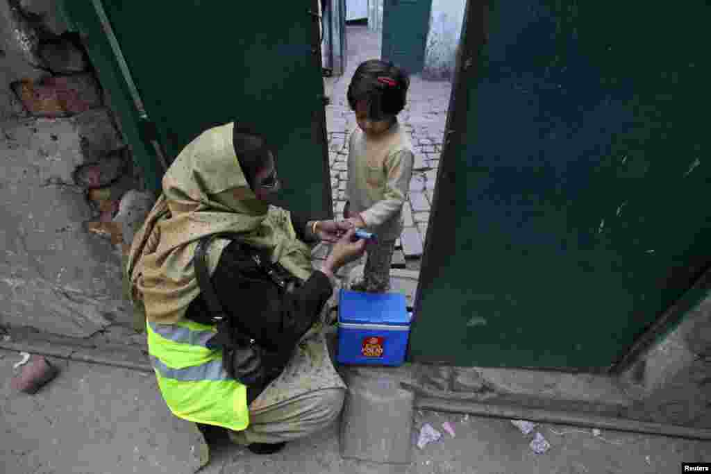 Petugas kesehatan bernama Nishat memberikan vaksin polio kepada seorang anak perempuan di Lahore (20/12/2012).