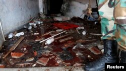 A Syrian Army soldier stands near blood on the ground of a damaged emergency room inside National Hospital after explosions hit the Syrian city of Jableh, May 23, 2016. 