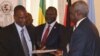 Taban Deng Gai (L), lead negotiator for the South Sudanese armed opposition, exchanges a signed recommitment to stop hostilities agreement with Nhial Deng, lead government negotiator, at an IGAD summit in Ethiopia on Nov. 9, 2014. Opposition leader Riek Machar looks on.