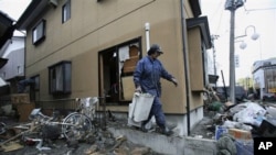A resident cleans up tsunami debris in his destroyed house Tuesday, March 15, 2011, in Soma city, Fukushima prefecture, Japan.