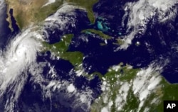This satellite image taken at 8:45 p.m. EDT on Oct. 22, 2015, and released by the National Oceanic and Atmospheric Administration shows Hurricane Patricia, left, moving over Mexico's central Pacific Coast.