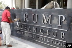 FILE - A man removes the word Trump off a marquee outside the Trump Ocean Club International Hotel and Tower in Panama City, March 5, 2018.