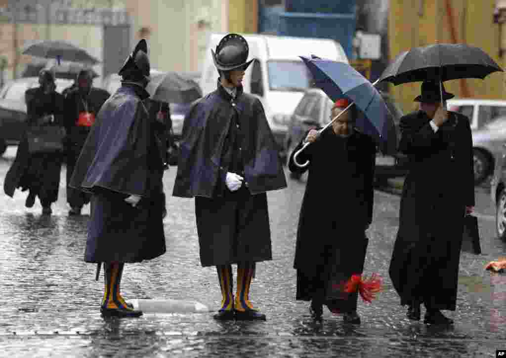 Cardinal Carlo Caffarra, second from right, and Cardinal Raymond Leo Burke, right, walk past two Swiss guards as they leave after a meeting at the Vatican, March 8, 2013. 