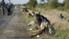 FILE - In this Dec. 14, 2008 file photo, children and their parents pick corn kernels spilled on the roadside by trucks ferrying corn imported from South Africa, in Masvingo 239 kilometers (148.5 miles) south of Harare. As the season of hunger and disease