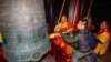 2018年12月31日，在中国海南省三亚的一座寺庙里，游客和僧人在新年前夕撞钟祈福，大钟上有“国泰民安”字样。