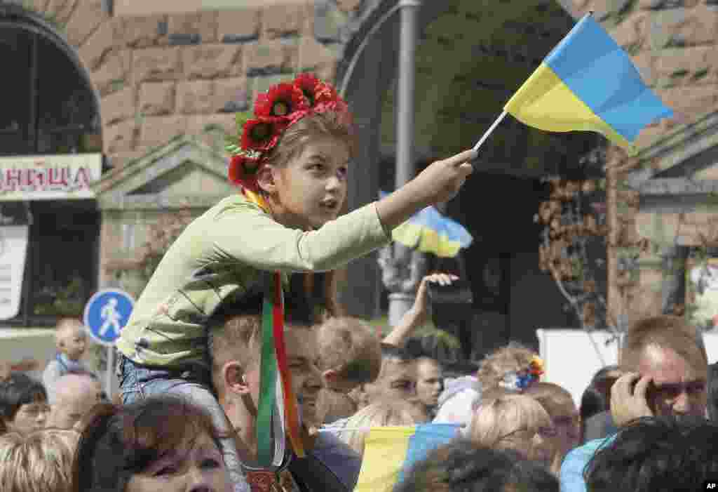 A Ukrainian girl waves the national flag sitting on her father's shoulders during celebration of Ukraine's 23rd Independence Day in Kiev, Ukraine, Aug. 24, 2014.