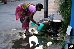 An Indian woman collects water leaking from a safety valve on an underground pipeline on World Water Day in Kolkata, India, March 22, 2017.