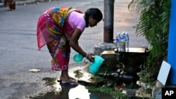 Seorang wanita mengumpulkan air yang bocor dari katup pengaman di sebuah jaringan air bawah tanah pada Hari Air Dunia di Kolkata, India tanggal 22 Maret 2017 (foto: AP Photo/Bikas Das)