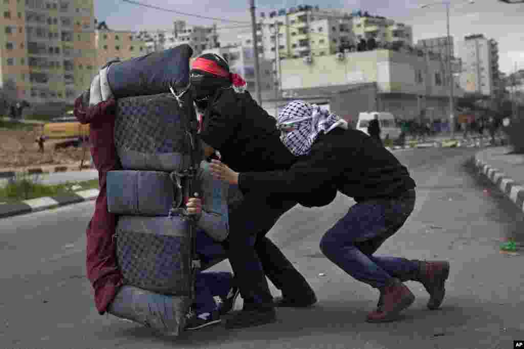 Những người Palestine d&ugrave;ng một chiếc ghế để che chắn trong cuộc biểu t&igrave;nh ủng hộ c&aacute;c t&ugrave; nh&acirc;n Palestine, b&ecirc;n ngo&agrave;i Ofer, một nh&agrave; t&ugrave; qu&acirc;n sự của Israel gần th&agrave;nh phố Ramallah v&ugrave;ng Bờ T&acirc;y