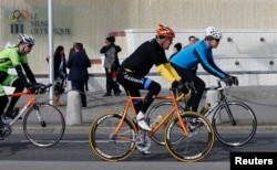 Menteri Luar Negeri AS John Kerry, tengah, bersepeda melewati Museum Olimpiade di Lausanne, Perancis, 16 Maret lalu.