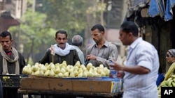 FILE - Egyptians buy fruits at a popular market in Cairo.