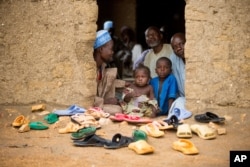 FILE - Refugees sit at the door of their home at the Minawao Refugee Camp in northern Cameroon.