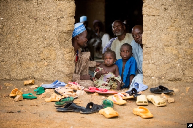 FILE - Refugees sit at the door of their home at the Minawao Refugee Camp in northern Cameroon.