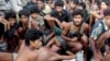 FILE - In this May 20, 2015, file photo, migrants including Myanmar's Rohingya Muslims sit on the deck of their boat as they wait to be rescued by Acehnese fishermen on the sea off East Aceh, Indonesia. Myanmar called sad and regrettable a move by the United States to place the country on a list of the world's worst human trafficking offenders, while rights groups welcome it as long overdue.