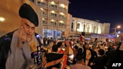 伊拉克议会选举的投票站关闭后，什叶派教士萨德尔的支持者在中部圣城纳贾夫庆祝。(2021年10月10日)