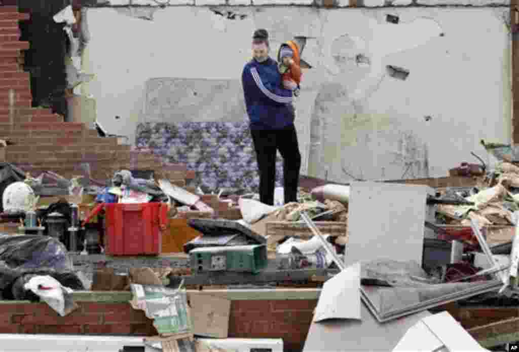 Ashley King and her son Dallas King look around a damaged house after a tornado struck in Marysville, Ind., Sunday, March 4, 2012.