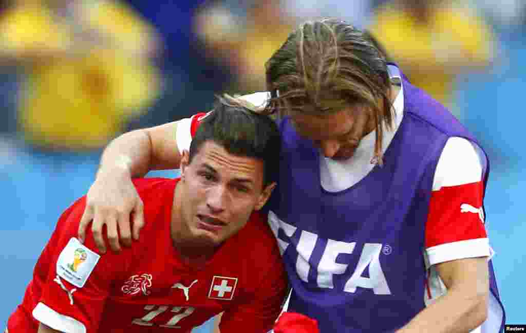 Switzerland&#39;s Michael Lang, right, comforts teammate Fabian Schaer after they are defeated by Argentina at the Corinthians arena in Sao Paulo, July 1, 2014.