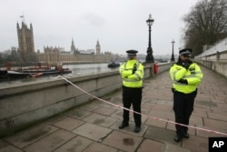 Police guard a cordon on the embankment with Britain's Houses of Parliament, left, in London, March 23, 2017, after attacks in London Wednesday.