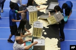 Election staff members open ballot boxes for vote counting in the upper house elections at a ballot counting center in Tokyo on July 10, 2016.