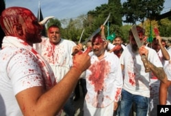 Lebanese Shi'ite men bleed from self-inflicted head wounds as they strike themselves with swords to show their grief during Ashura rituals, in the southern market town of Nabatieh, Oct. 12, 2016.